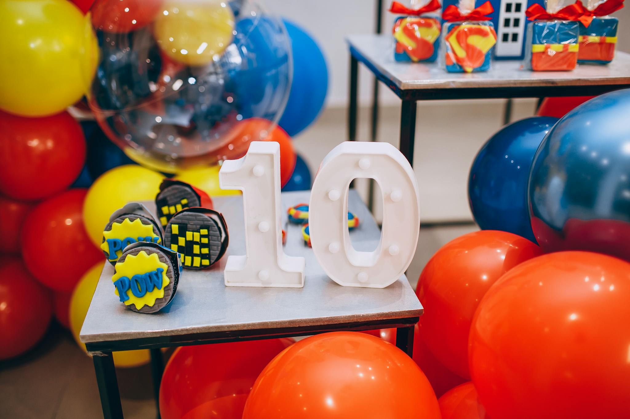 Vibrant celebration setup with balloons, number 10, and superhero-themed cupcakes.